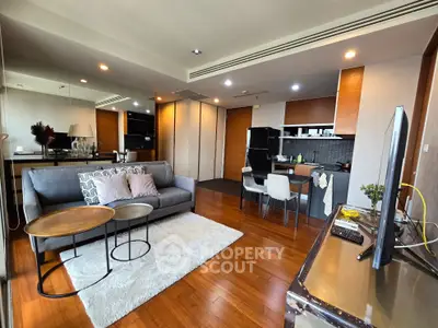 Modern open-plan living room with stylish kitchen and cozy seating area, featuring hardwood floors and contemporary decor.