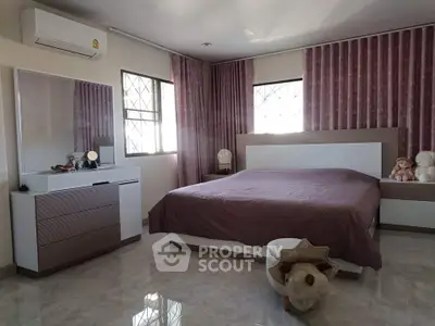 Spacious bedroom with modern decor and large windows for natural light.