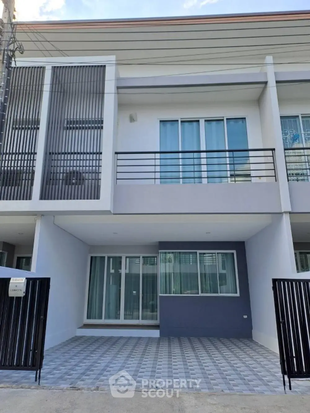 Modern two-story townhouse with spacious balcony and secure parking, featuring sleek design and large windows for abundant natural light.