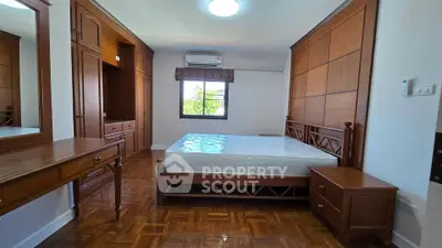 Spacious bedroom with wooden furniture and large window view