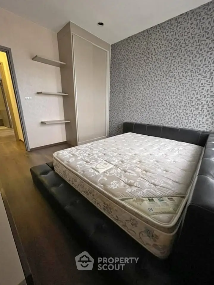 Modern bedroom with stylish wallpaper and built-in wardrobe, featuring a comfortable bed and sleek wooden flooring.