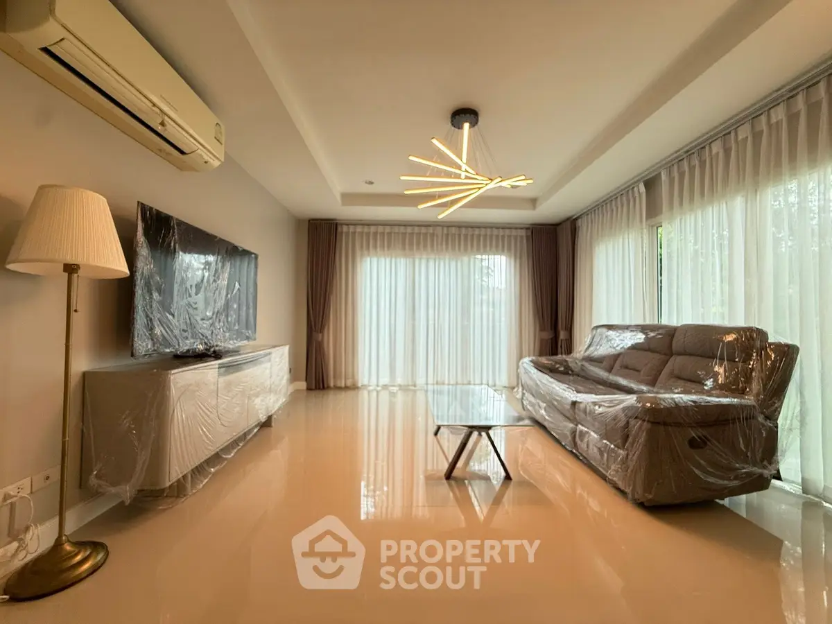 Modern living room with stylish lighting, large windows, and sleek furniture for a luxurious ambiance.