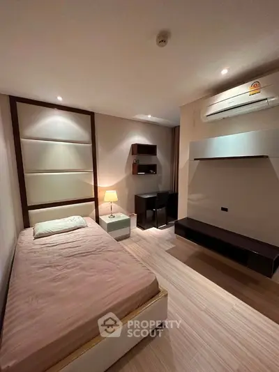 Cozy bedroom with modern furnishings and ambient lighting, featuring a single bed and workspace.