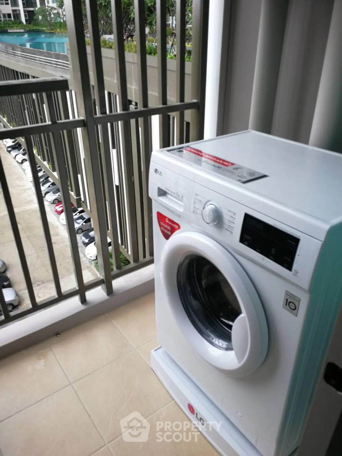 Modern apartment balcony with washing machine and pool view, ideal for urban living.
