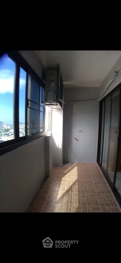 Spacious balcony with city view and large windows in modern apartment.