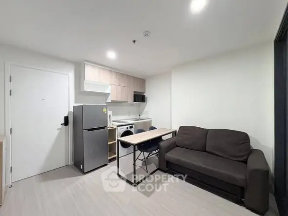 Modern compact living room with kitchenette, featuring a cozy sofa and sleek appliances for urban living.