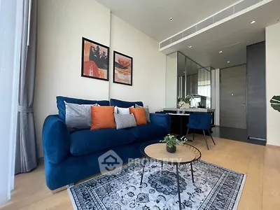 Modern living room with blue sofa, stylish decor, and elegant dining area in a contemporary apartment.