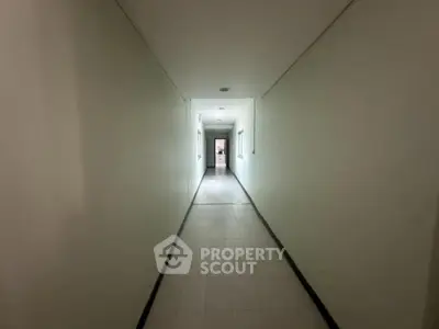 Spacious hallway with tiled flooring and neutral walls in modern building