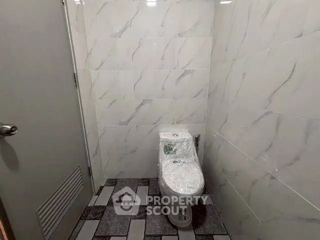Modern bathroom with marble tiles and sleek toilet design.