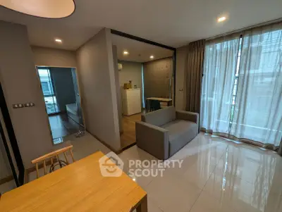Modern living room with sleek furniture and natural light, featuring a cozy sofa and dining area.