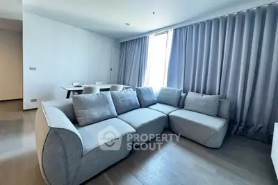 Spacious modern living room with stylish gray sofa and elegant dining area, perfect for contemporary living.