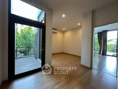 Spacious modern living room with large windows and balcony access, featuring elegant wooden flooring.