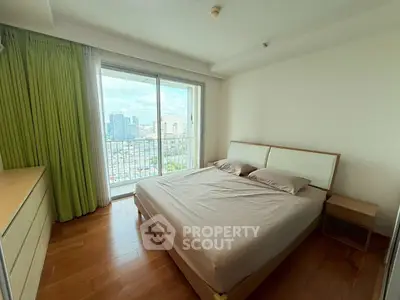 Spacious bedroom with city view and balcony access in modern apartment
