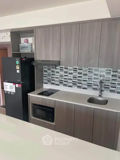 Modern kitchen with sleek cabinetry and built-in appliances, featuring a stylish backsplash.