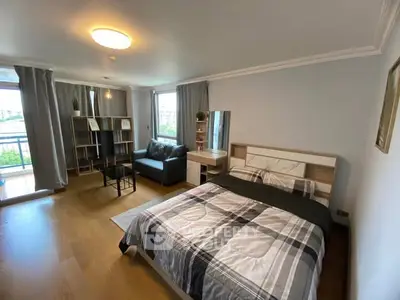 Spacious bedroom with modern decor and balcony view in urban apartment.