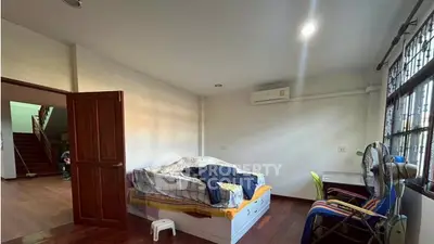 Spacious bedroom with wooden flooring and large window for natural light.