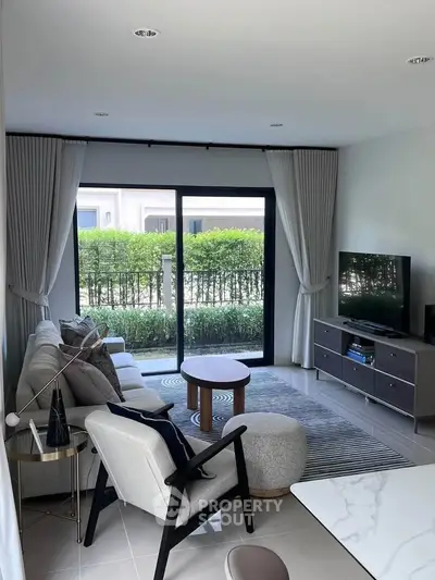 Modern living room with stylish furniture and garden view through large windows.