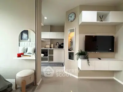 Modern living room with sleek TV setup and cozy kitchen area in open layout apartment.
