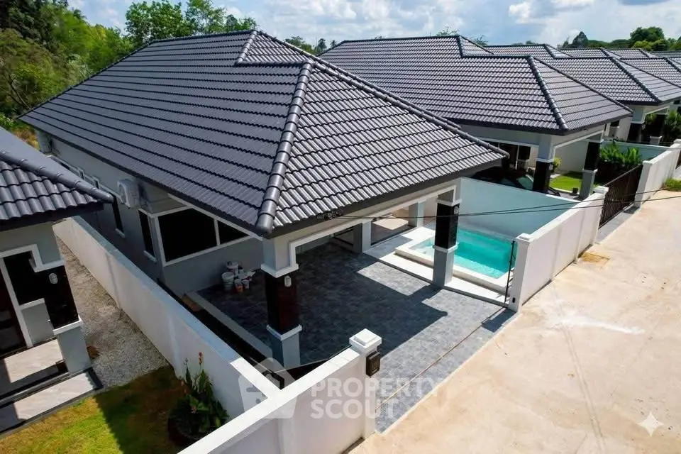 Modern single-story house with private pool and sleek roof design in a serene neighborhood.