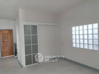 Spacious interior with sliding door and glass block window, ideal for modern living.