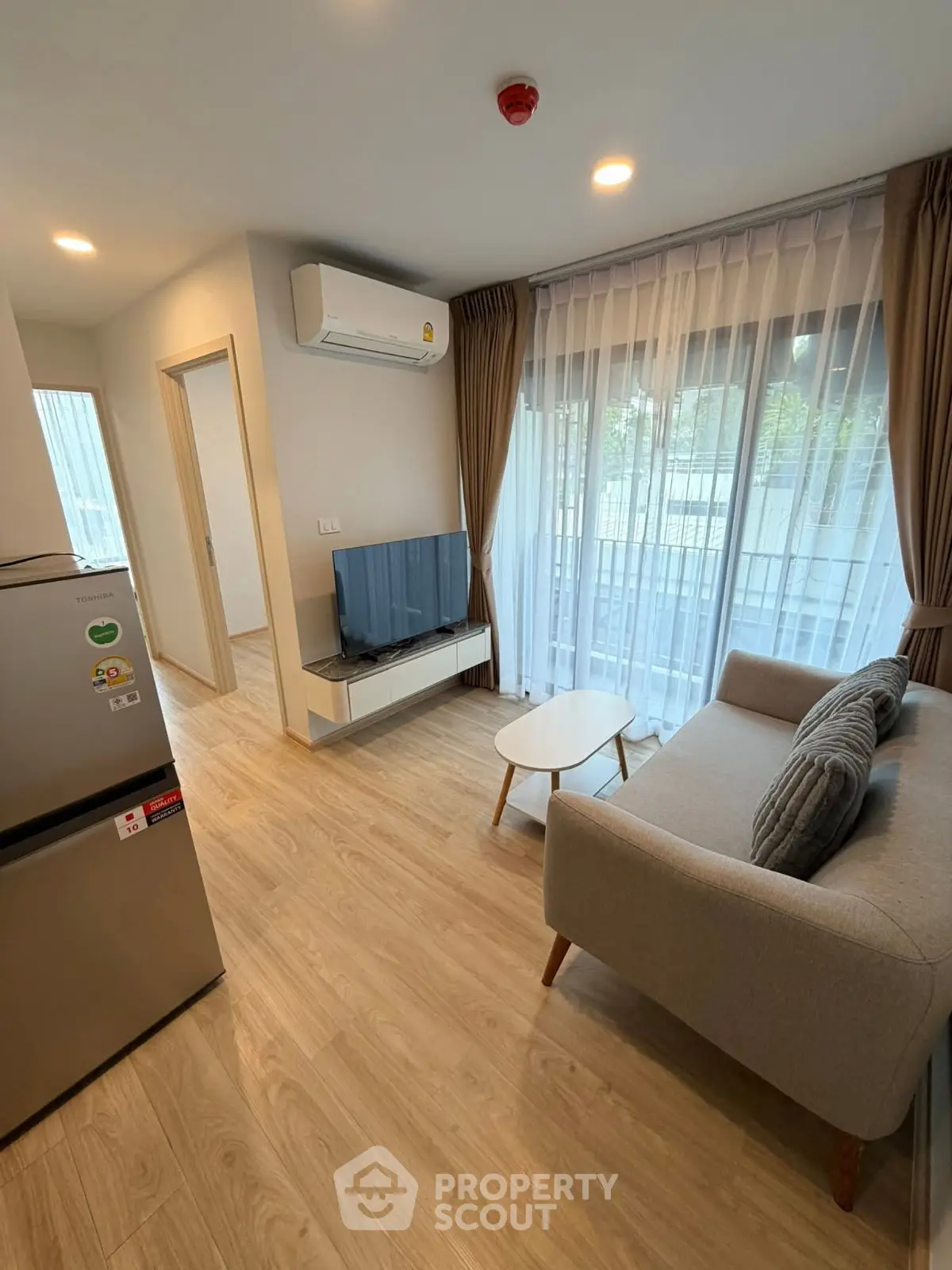 Modern living room with natural light, cozy sofa, and sleek TV setup in a stylish apartment.