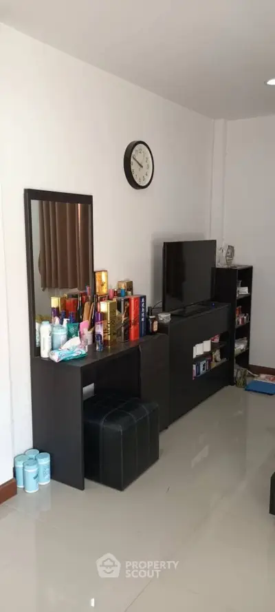 Modern living room with sleek black furniture and wall clock