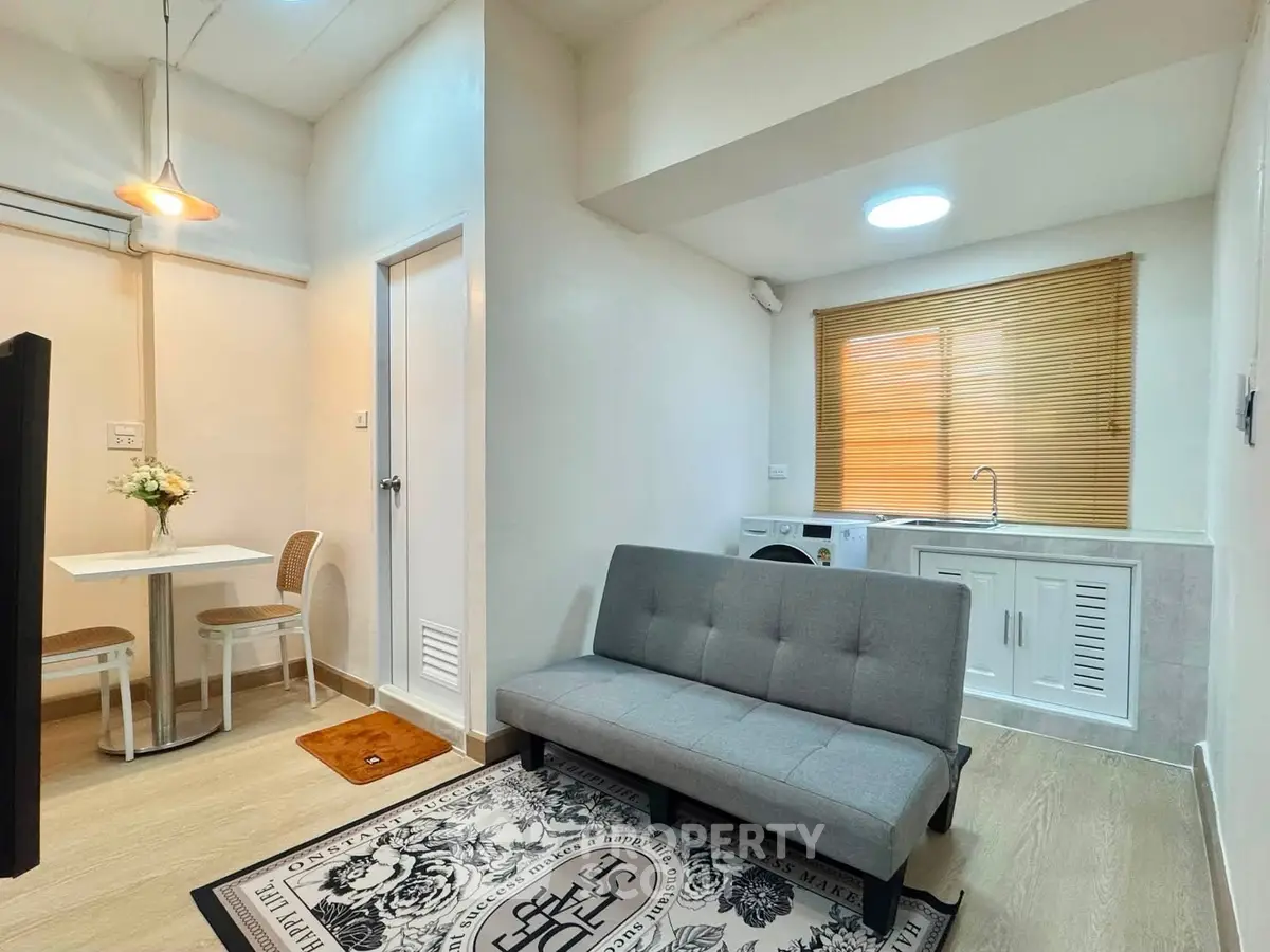 Cozy living room with modern decor and compact kitchen in open layout apartment.