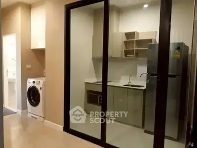 Modern kitchen with glass partition, washing machine, and sleek appliances.