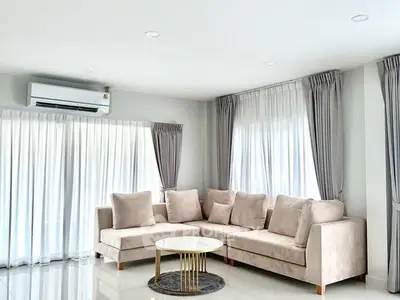 Spacious living room with modern beige sectional sofa and elegant curtains