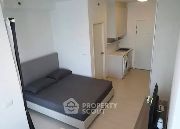 Modern studio apartment with compact kitchen and cozy bedroom area.