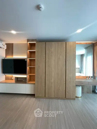 Modern living room with sleek wooden cabinetry and built-in TV, featuring elegant lighting and spacious design.