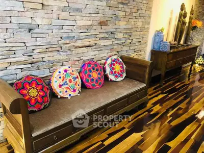 Charming interior with rustic stone wall and vibrant cushions on wooden bench, perfect for cozy living spaces.