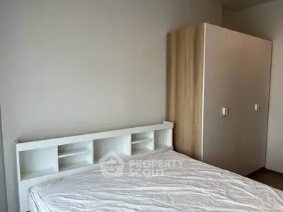 Modern bedroom with minimalist design featuring a sleek white bed and wooden wardrobe.