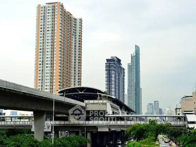 Modern urban skyline with high-rise buildings and elevated train tracks in a bustling cityscape.