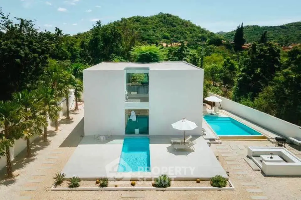 Modern minimalist villa with private pool and lush green surroundings