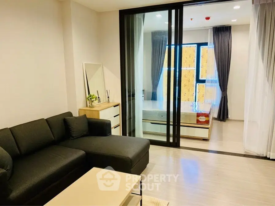 Modern living room with glass partition leading to cozy bedroom