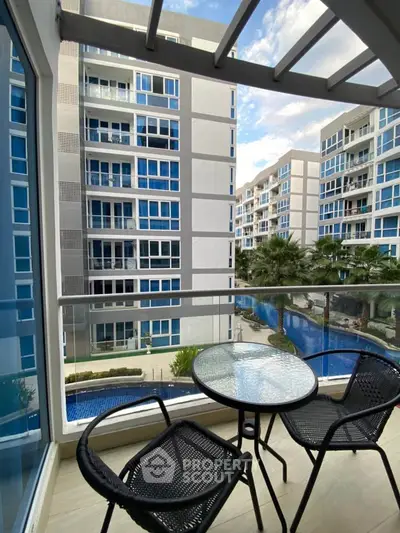 Modern balcony view overlooking a stylish apartment complex with pool and palm trees.