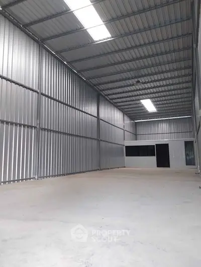Spacious industrial warehouse with high ceilings and metal walls, ideal for storage or manufacturing.