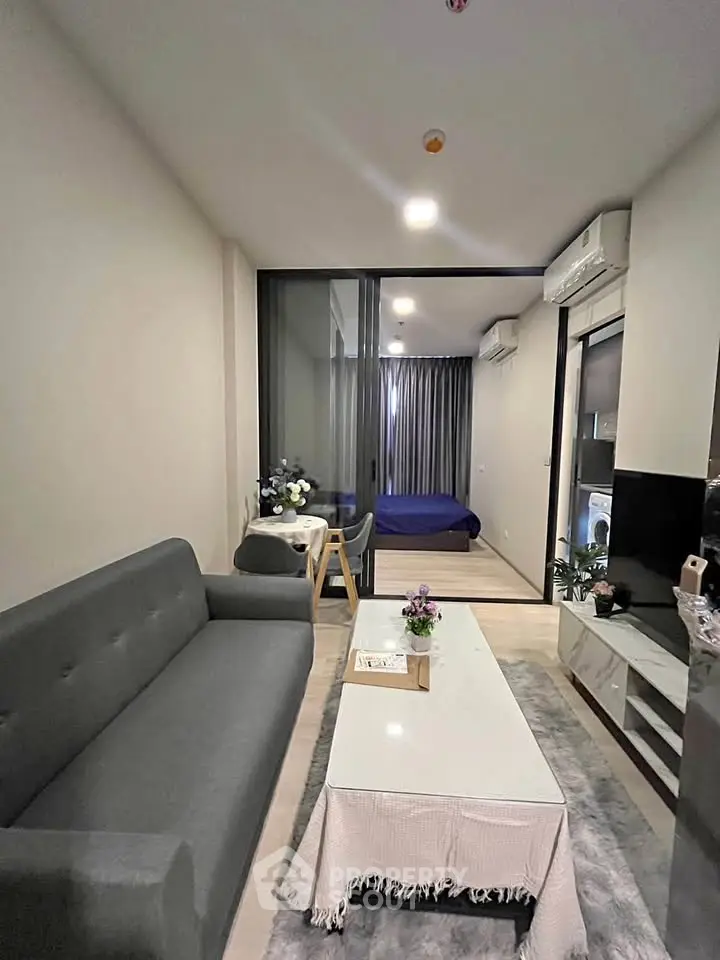 Modern living room with sleek furniture and a view into a cozy bedroom