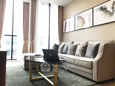 Modern living room with elegant sofa, large windows, and stylish decor in a bright apartment.