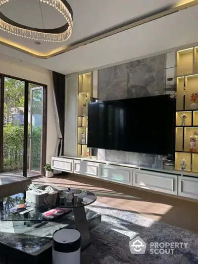 Luxurious living room with modern decor and large TV, featuring elegant lighting and glass coffee table.