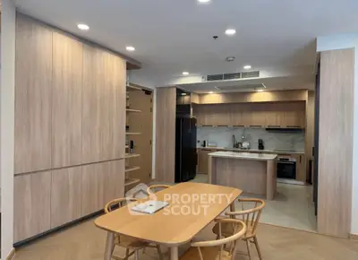 Modern kitchen with open layout and wooden dining area, featuring sleek cabinetry and integrated appliances.