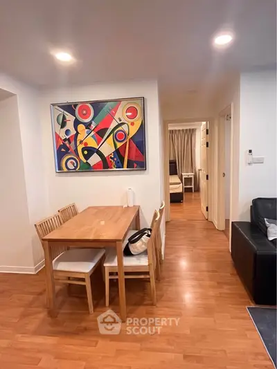 Modern living room with wooden dining set and abstract art, showcasing cozy and stylish interior design.
