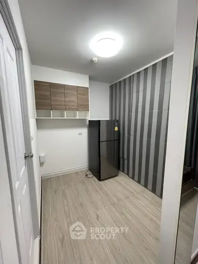Modern kitchen with sleek fridge and stylish cabinetry in compact space.
