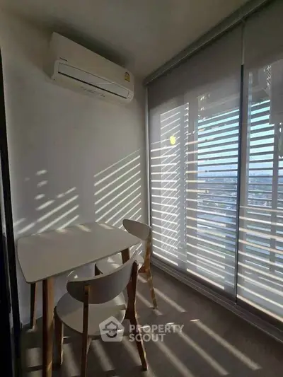 Cozy study nook with modern table and chairs, featuring natural light through blinds and air conditioning.