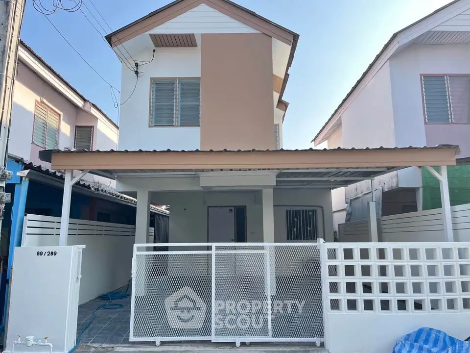 Charming two-story house with modern facade and gated entrance in a serene neighborhood.