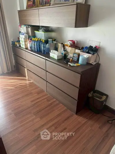 Spacious storage area with modern wooden cabinets and organized cleaning supplies.