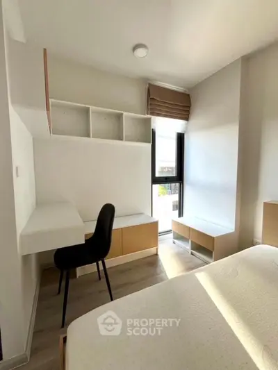 Modern bedroom with natural light, built-in desk, and storage solutions.