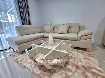Stylish living room with modern beige sectional sofa and elegant glass coffee table on plush rug.