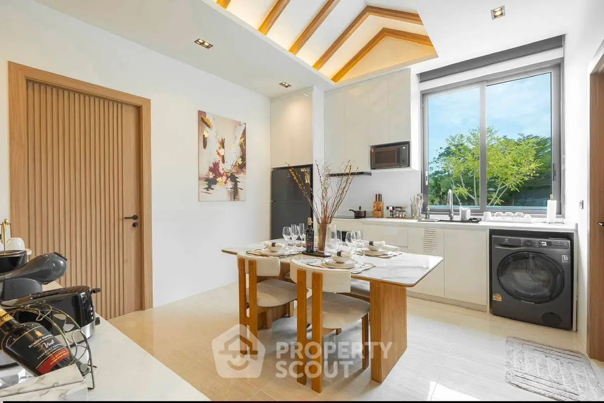 Modern kitchen with dining area, featuring sleek appliances and large window with garden view.